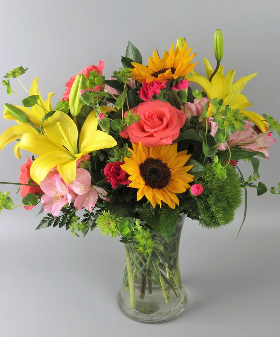 Vase of vibrant color flowers with sunflowers, lilies, roses